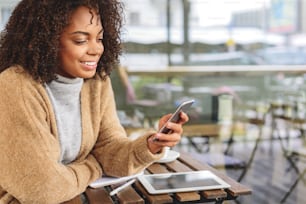 female blogger in cozy wear using a smartphone in a public place