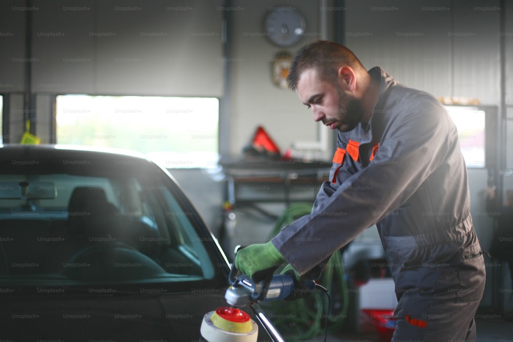 Mechanic changing glass on car in his workshop.