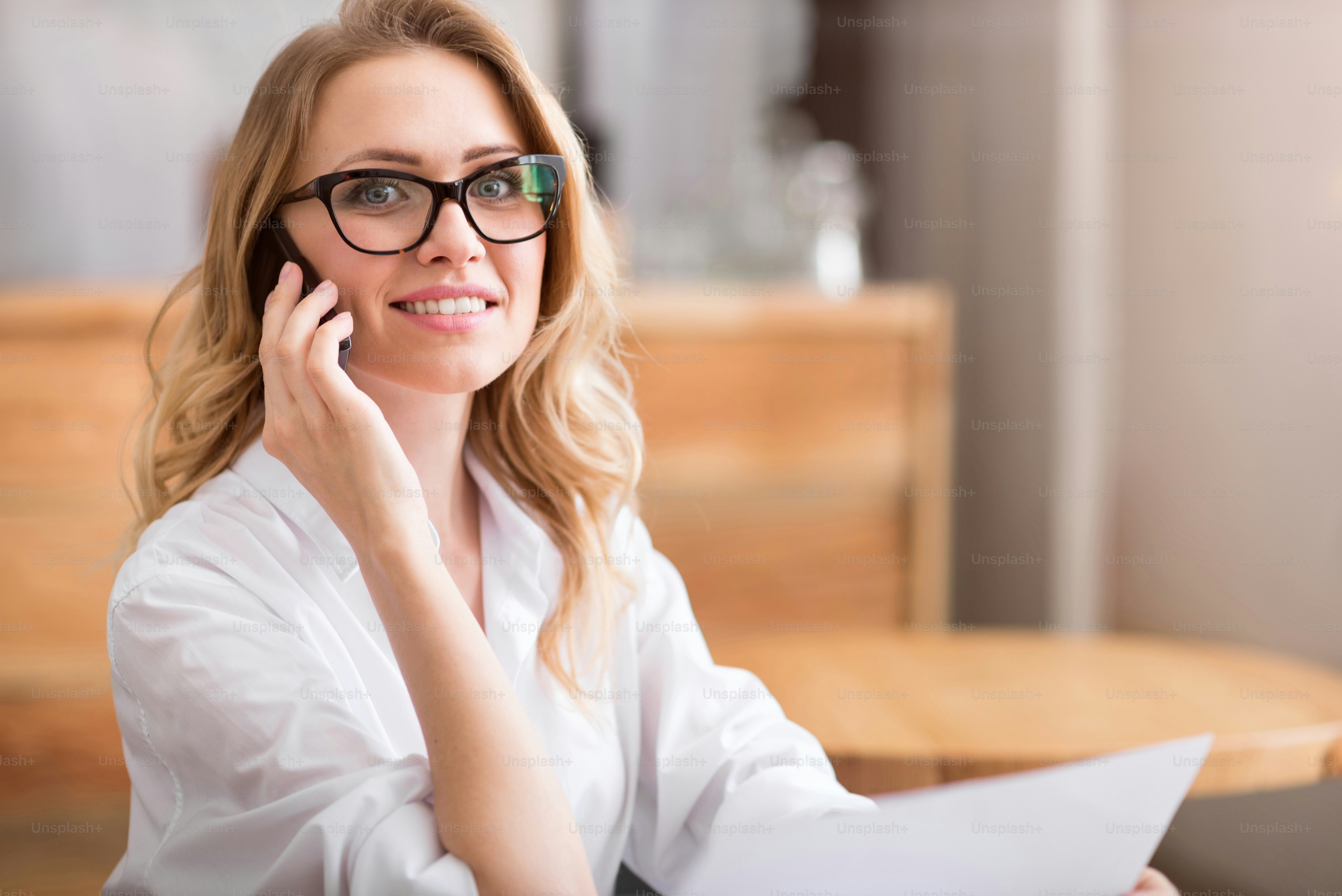 Sorriso encantador. Retrato da mulher jovem feliz e alegre falando por telefone inteligente e sorrindo para a câmera