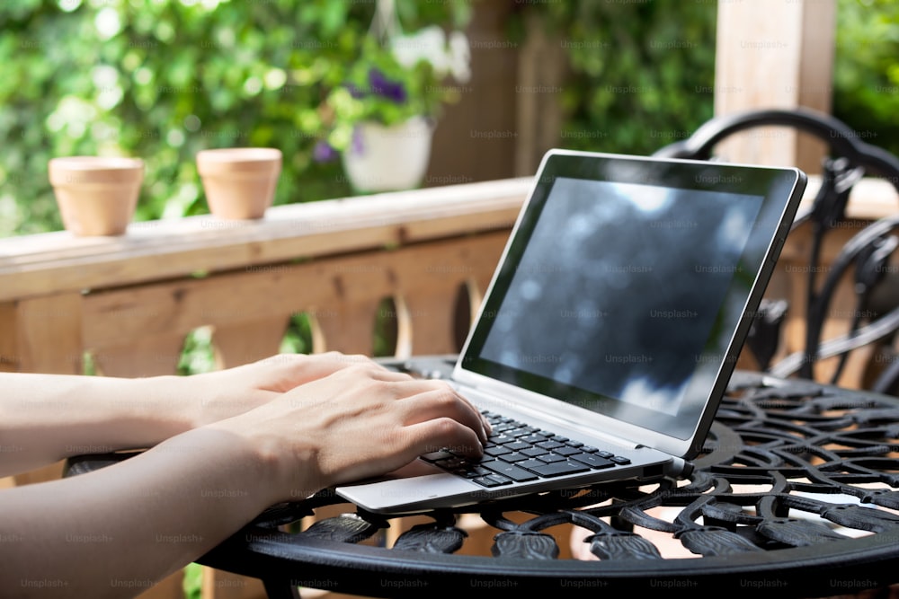 노트북/비즈니스 태블릿이 있는 테라스에서 금속 테이블에 키보드로 작업