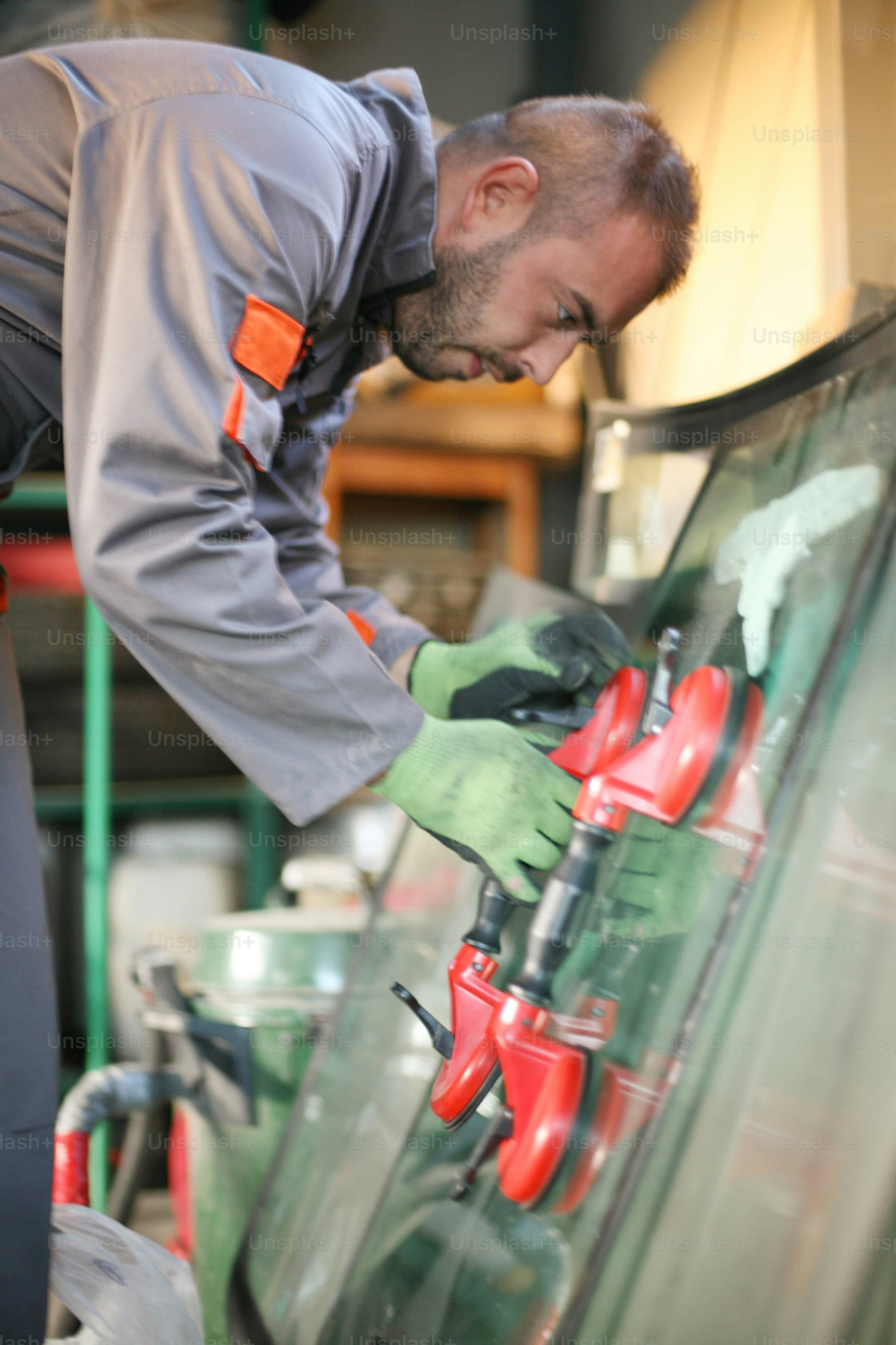 Mecânico trocando vidro para carro em oficina.