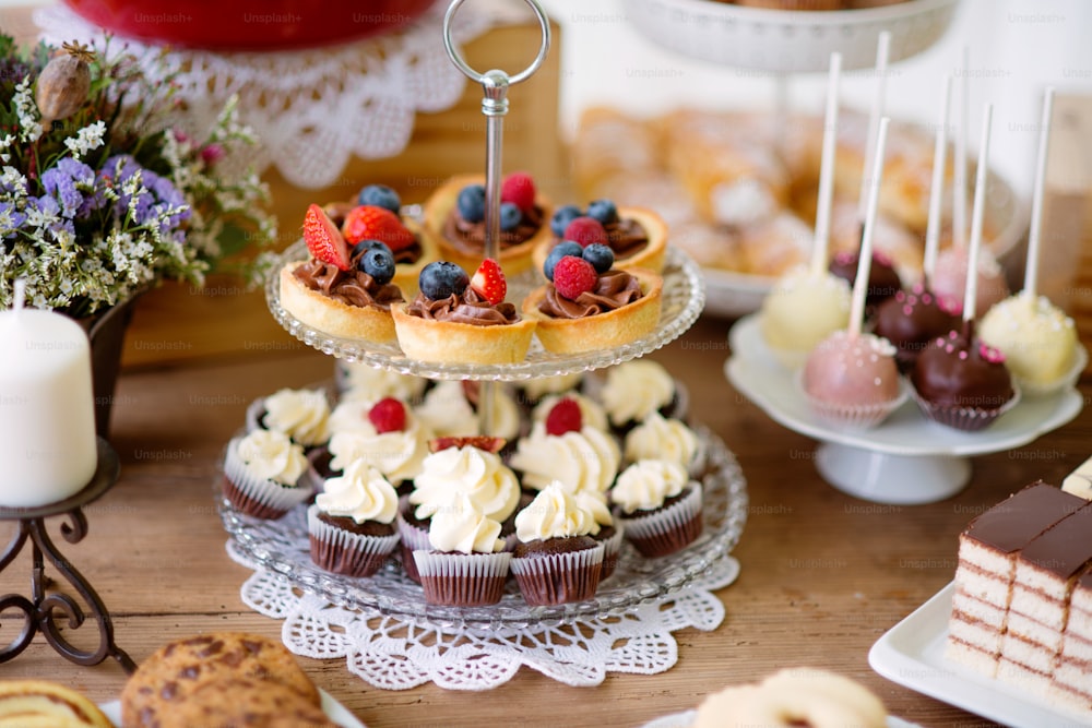 다양한 쿠키, 타르트, 케이크, 컵케이크, 케이크팝이 있는 갈색 나무 테이블. 스튜디오 촬영.