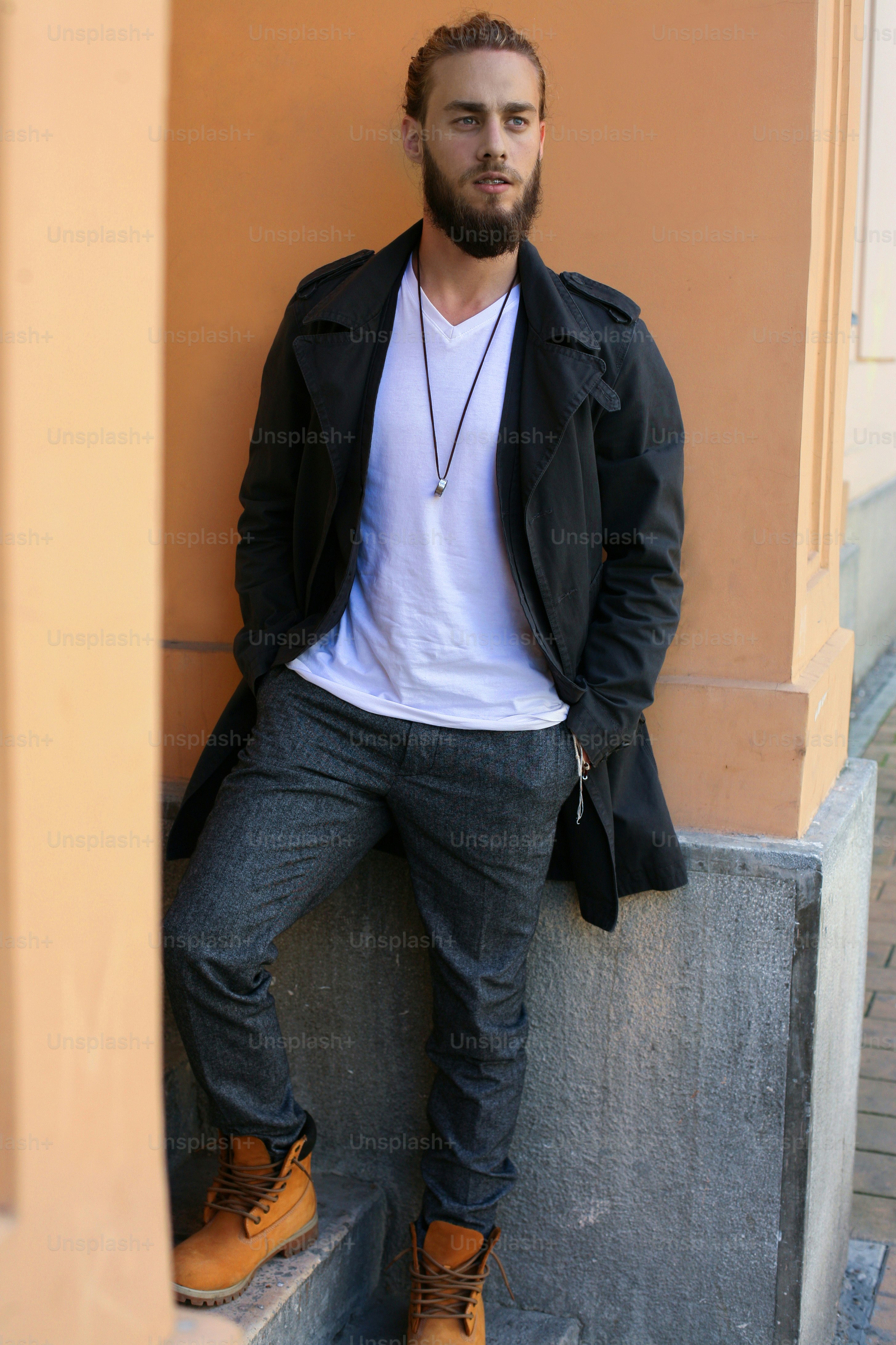 Young handsome hippie man leaning on wall.