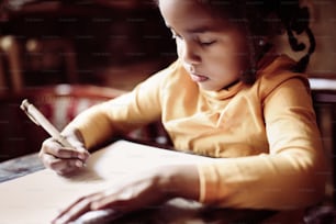 Little African girl writing  at home.