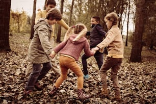 Groupe de cinq personnes s’amusant dans le parc d’automne.