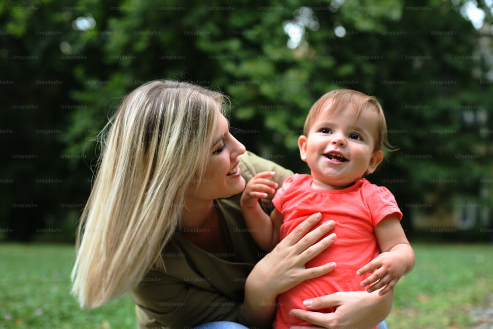 Adorable baby with her mother paying in the park.