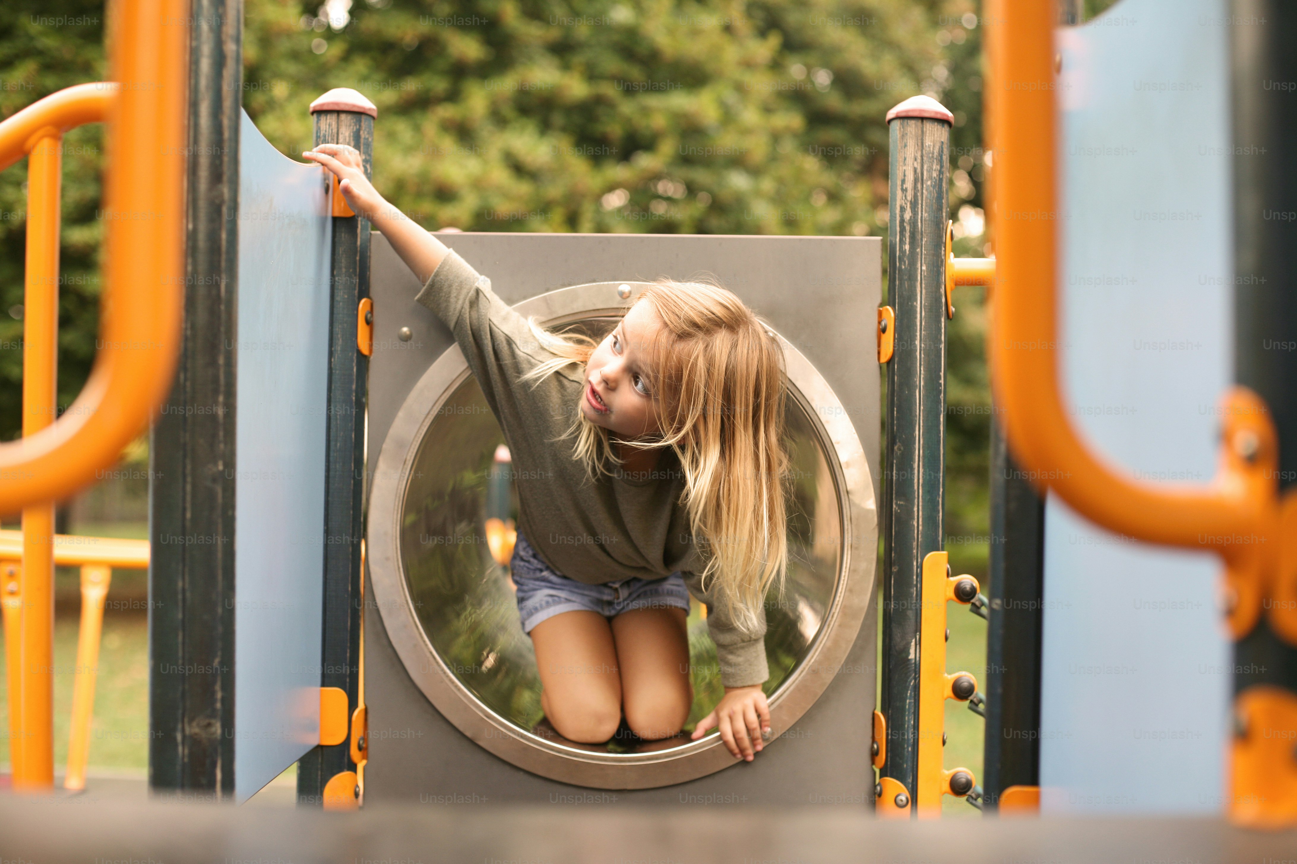 La niña está escalando en el patio de recreo