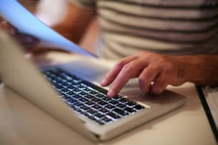 Hombre mayor pagando facturas en línea en una computadora portátil.