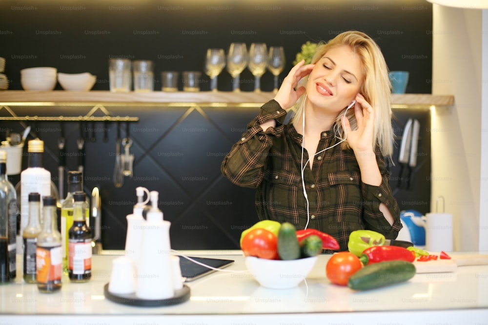 Mujer escuchando música y preparando una comida saludable.