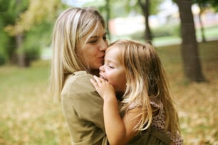 Mother with her daughter playing in the park. Mother hugging her daughter.