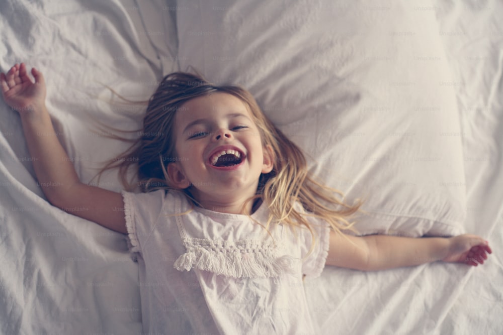Petite fille joyeuse au lit.
