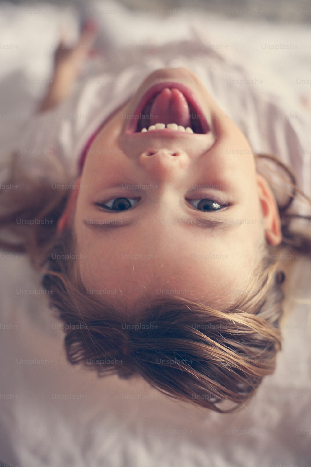 Fun in bed. Cute little girl i bed, looking at the camera.