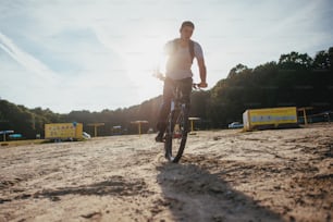Attractive Biker riding along beach at sunset