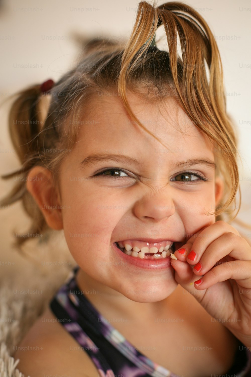 Petite fille montrant sa première dent mobile. Regarder la caméra.