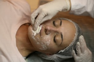 Mulher nova em um centro de spa. Deitada em uma mesa de massagem com uma máscara no rosto.