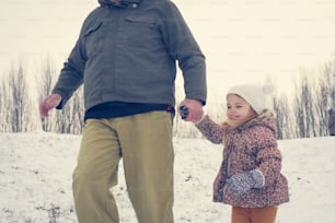 Grandfather and granddaughter  walking in the snow.