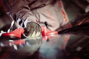 Mechanic changing glass in his workshop. Focus is on hand.