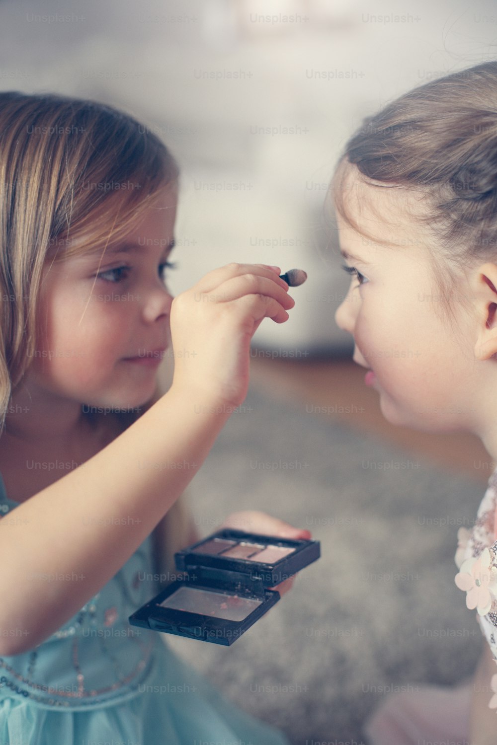 Two little girl helping each other to put shadows on their face.