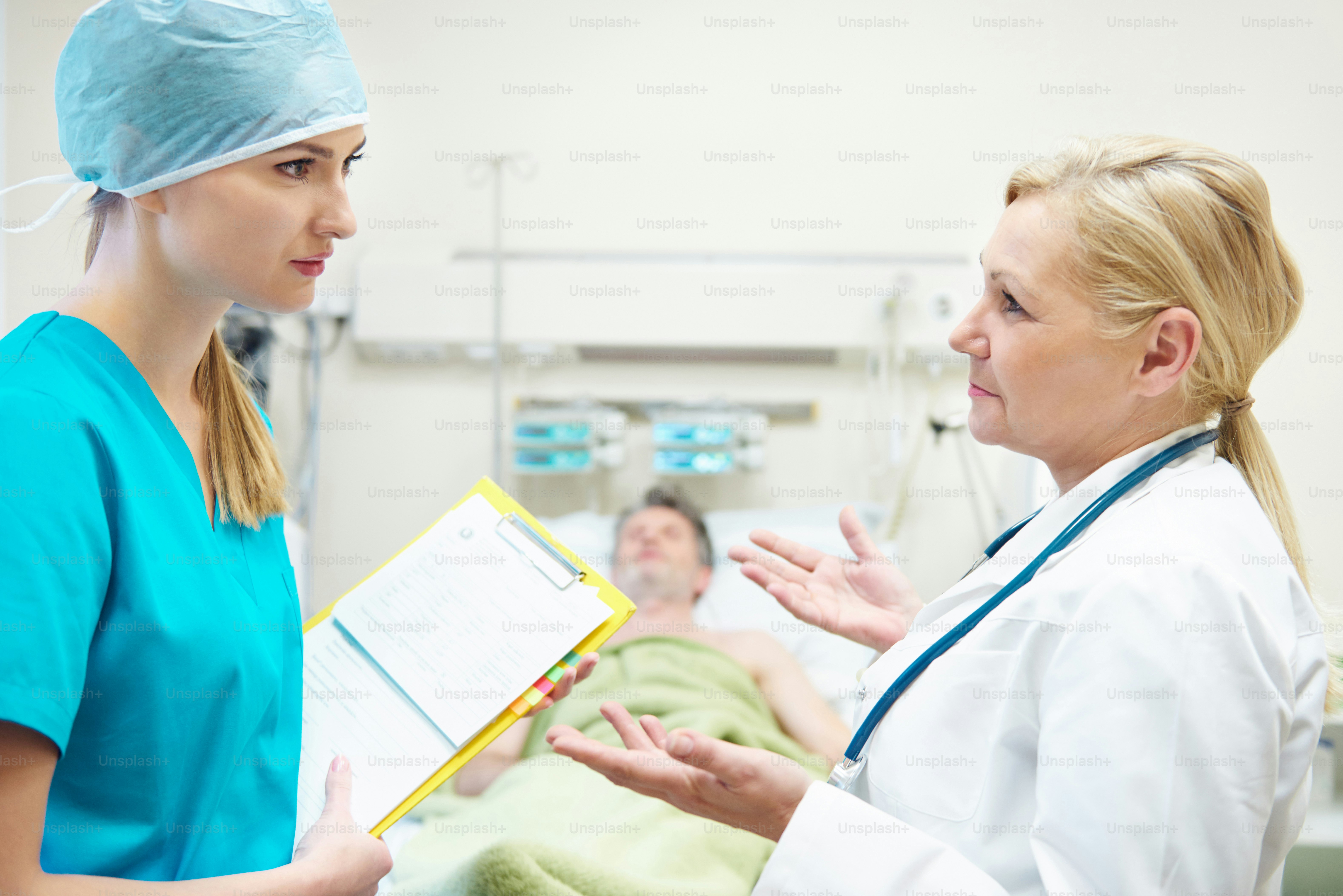 Doctors talking next to sleeping patient