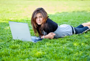 woman on grass with laptop in summer park