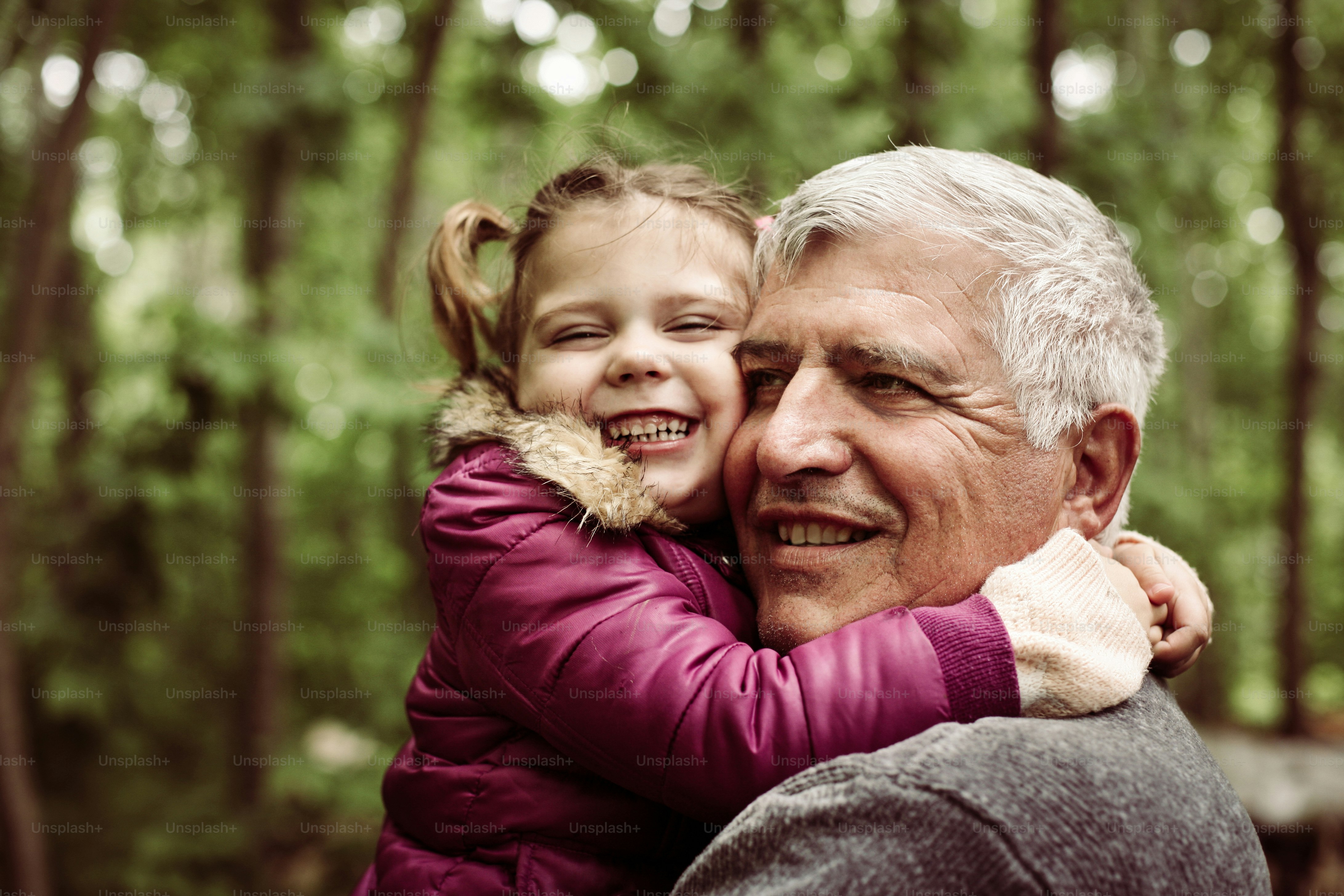 Happy kid hugging grandfather in the park. Focus on grandfather.