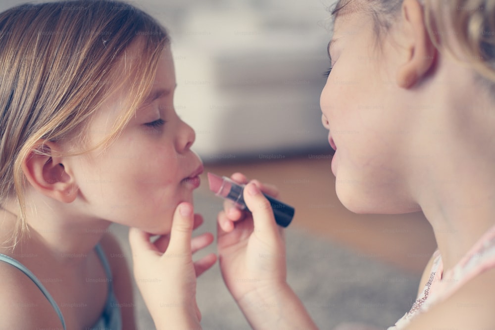 Cute little girls playing with make up in the room.