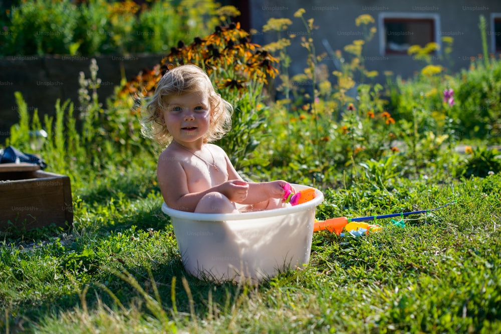 criança feliz brincando na água perto da casa no gramado