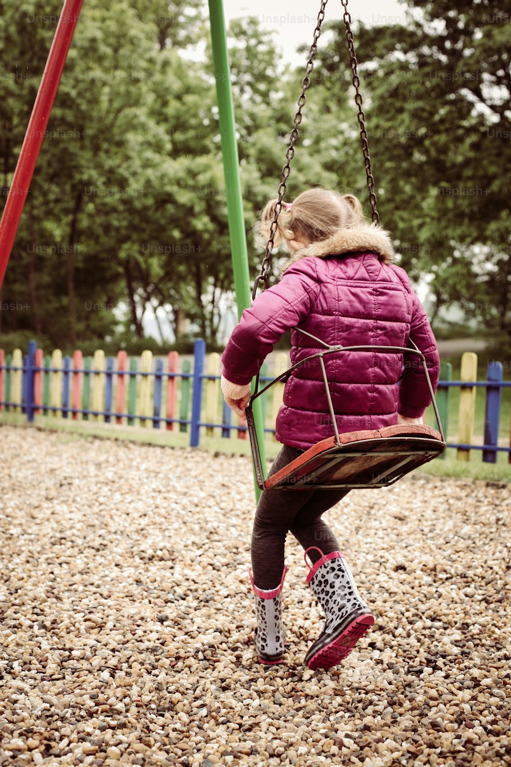 Little girl swinging on a playground in  park.