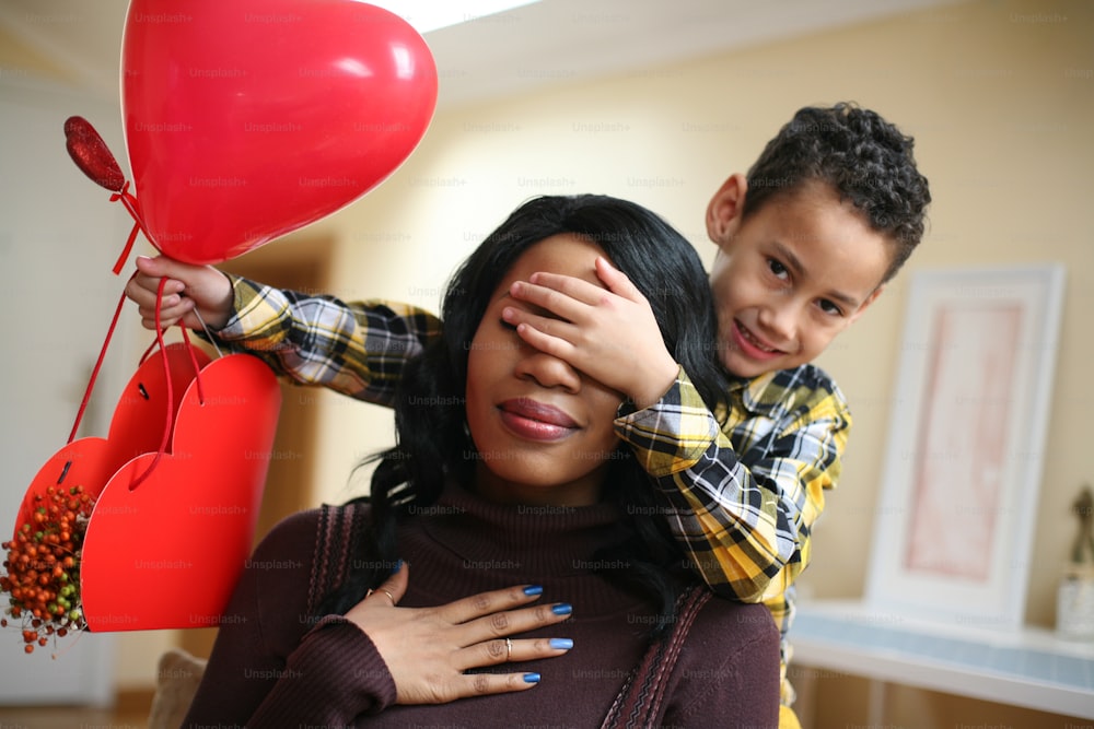 African American boy holding his mother closed eyes."n