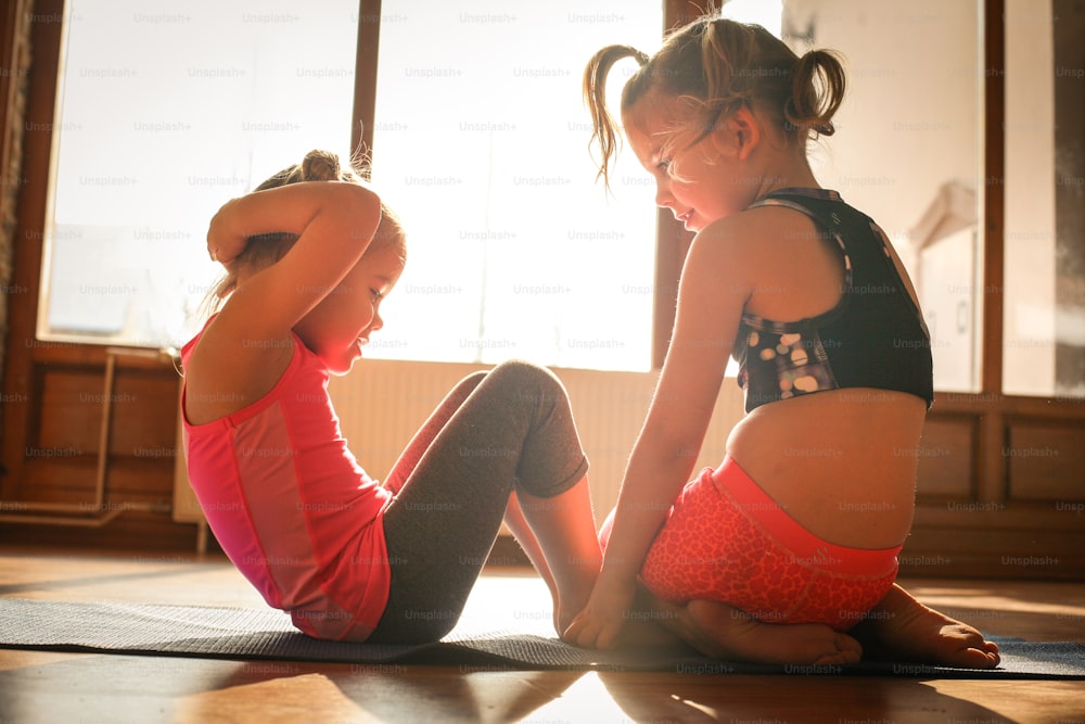 Family support. Two little sisters workout together at home.