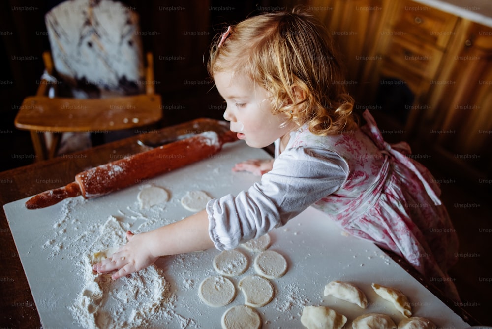 Bäckermädchen knetet den Teig und formt Kuchen in der Küche