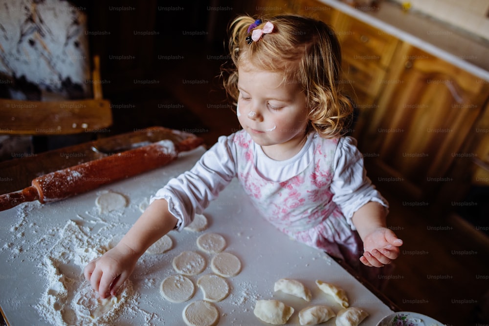 パン屋の女の子は、キッチンで生地をこねてケーキを形作ります