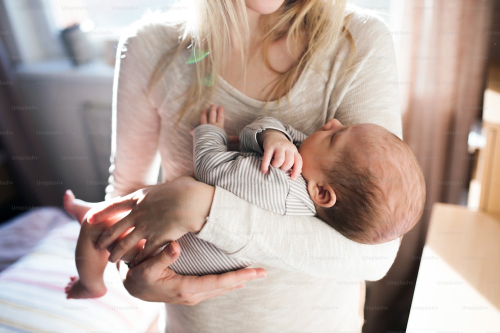 赤ん坊の息子を腕に抱く見分けのつかない若い母親