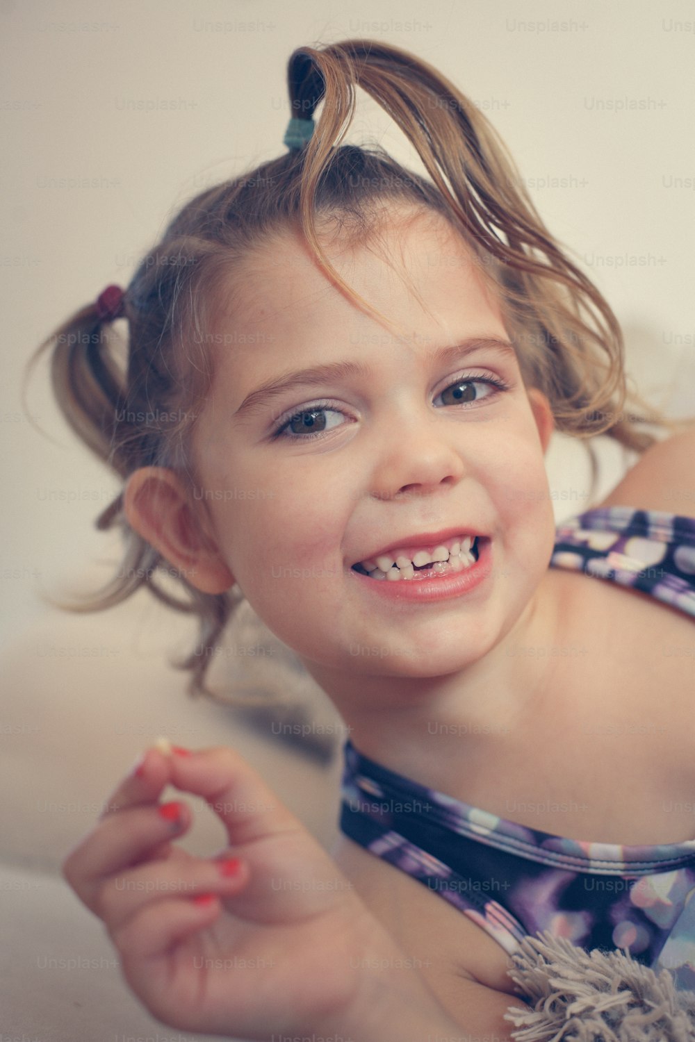 Petite fille montrant sa première dent mobile. Regarder la caméra.