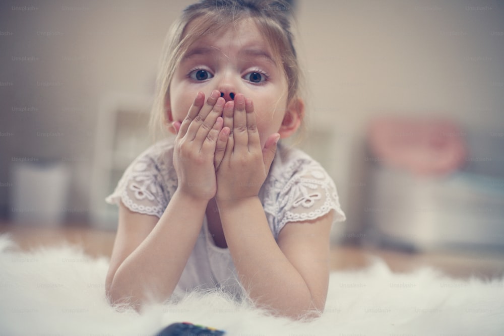 Bambina scioccata che guarda qualcosa in TV.