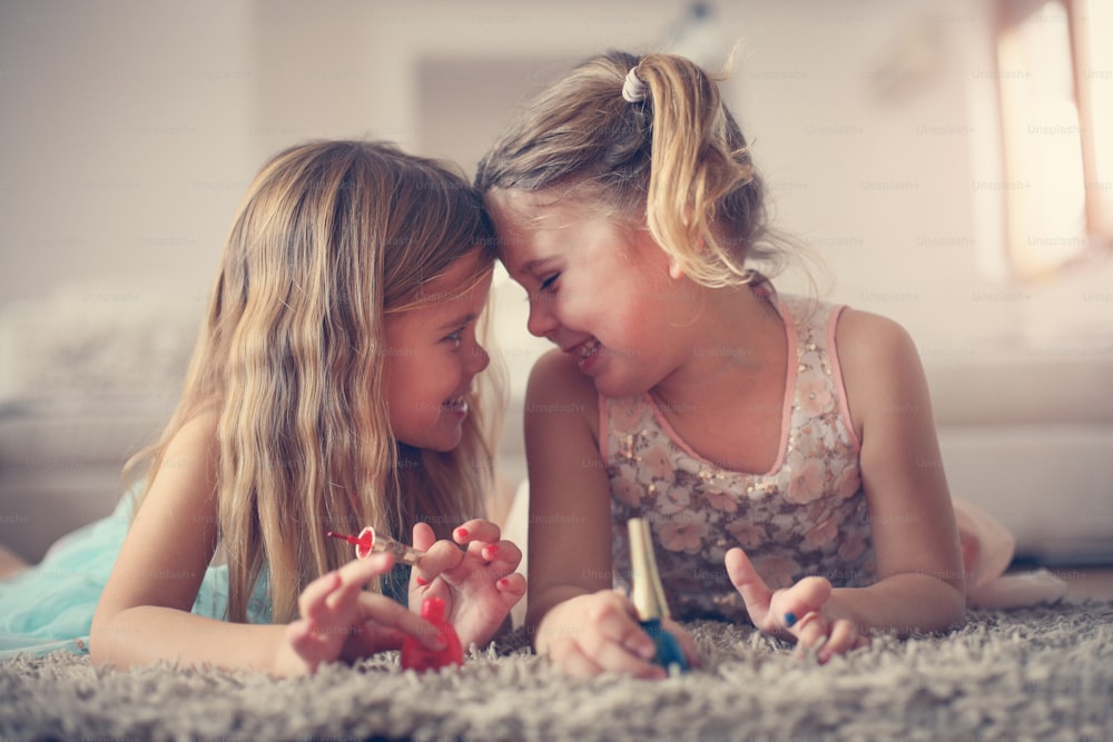 Two little girls painted their nails at home.