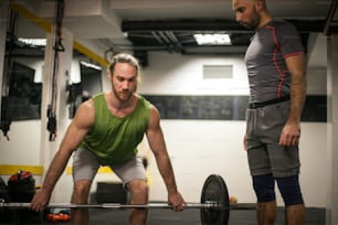 Adult man doing weightlifting in a gym.