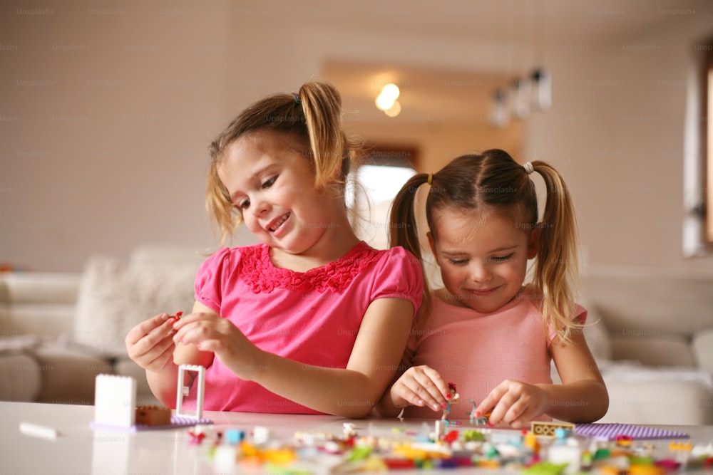 Des filles jouant avec des blocs de plastique à la maison.