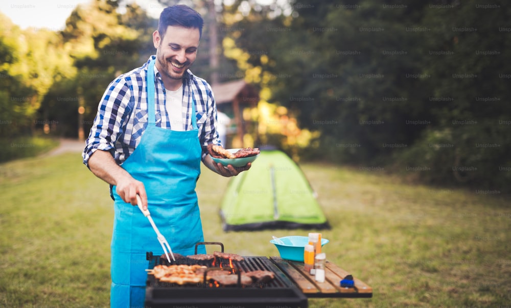 Handsome man preparing barbecue for friends outdoor