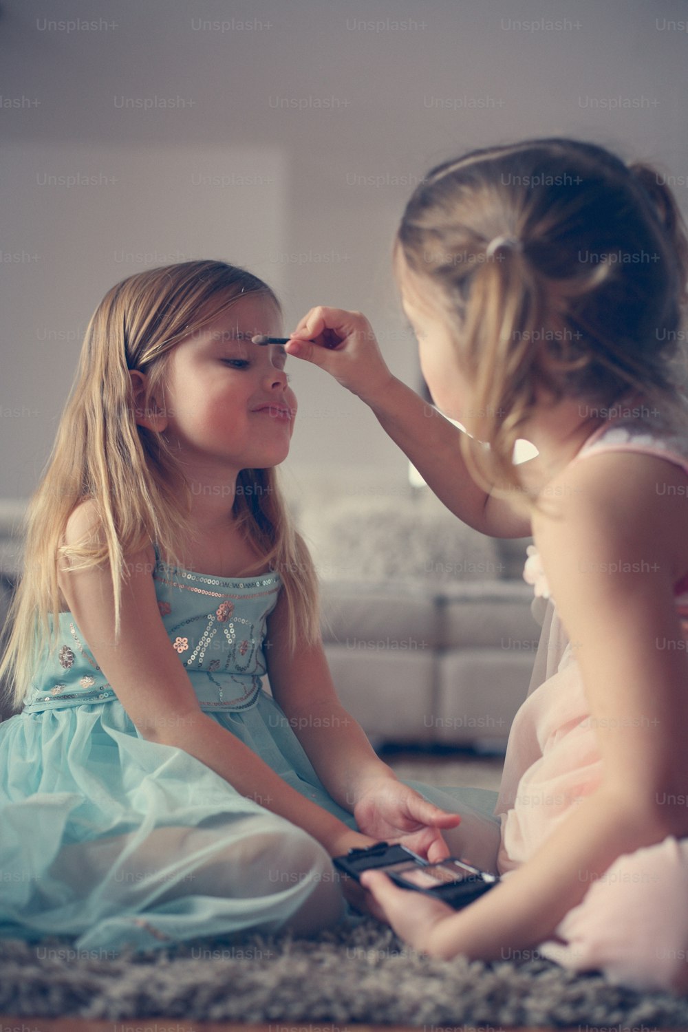 Two little girl helping each other to put shadows on their face.