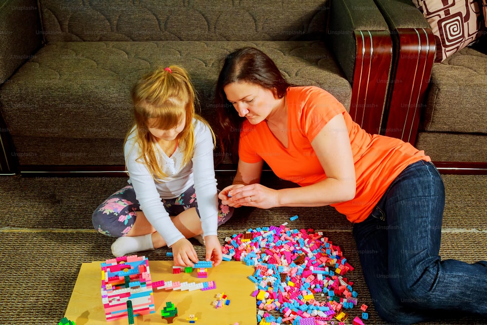 Mother and child daughter playing together, build from the constructor. cute mother play together indoor. Young mom with her child play together