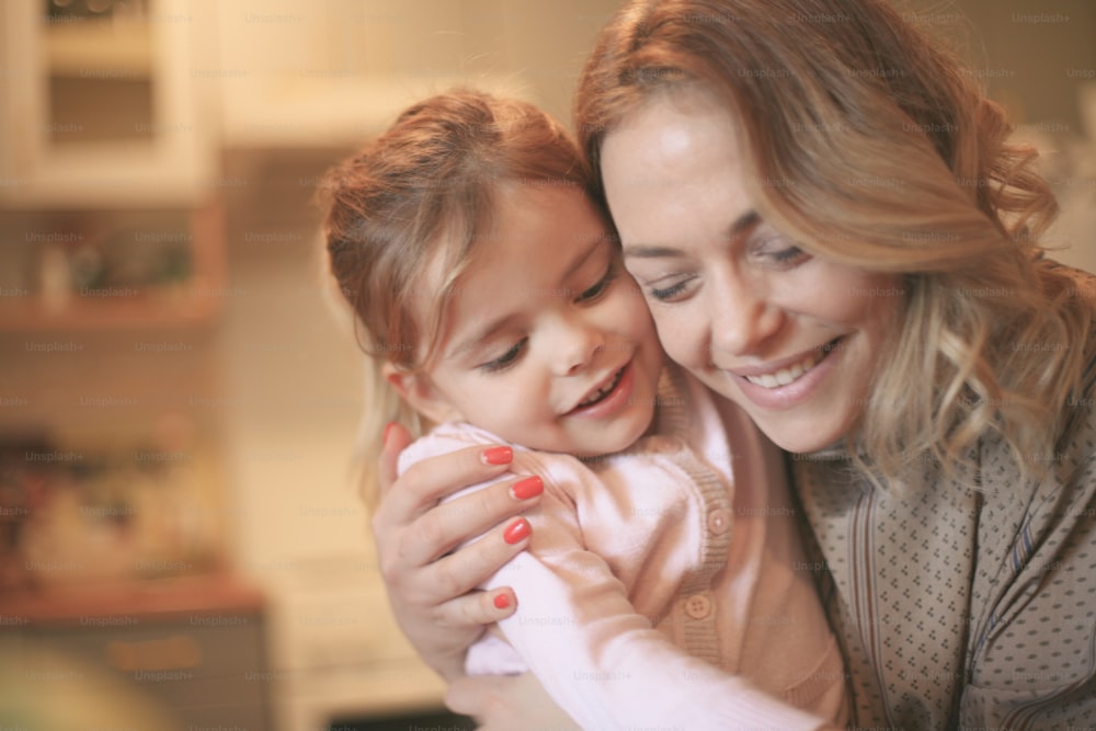 Beautiful blonde Caucasian girl embracing her mother and smiling.
