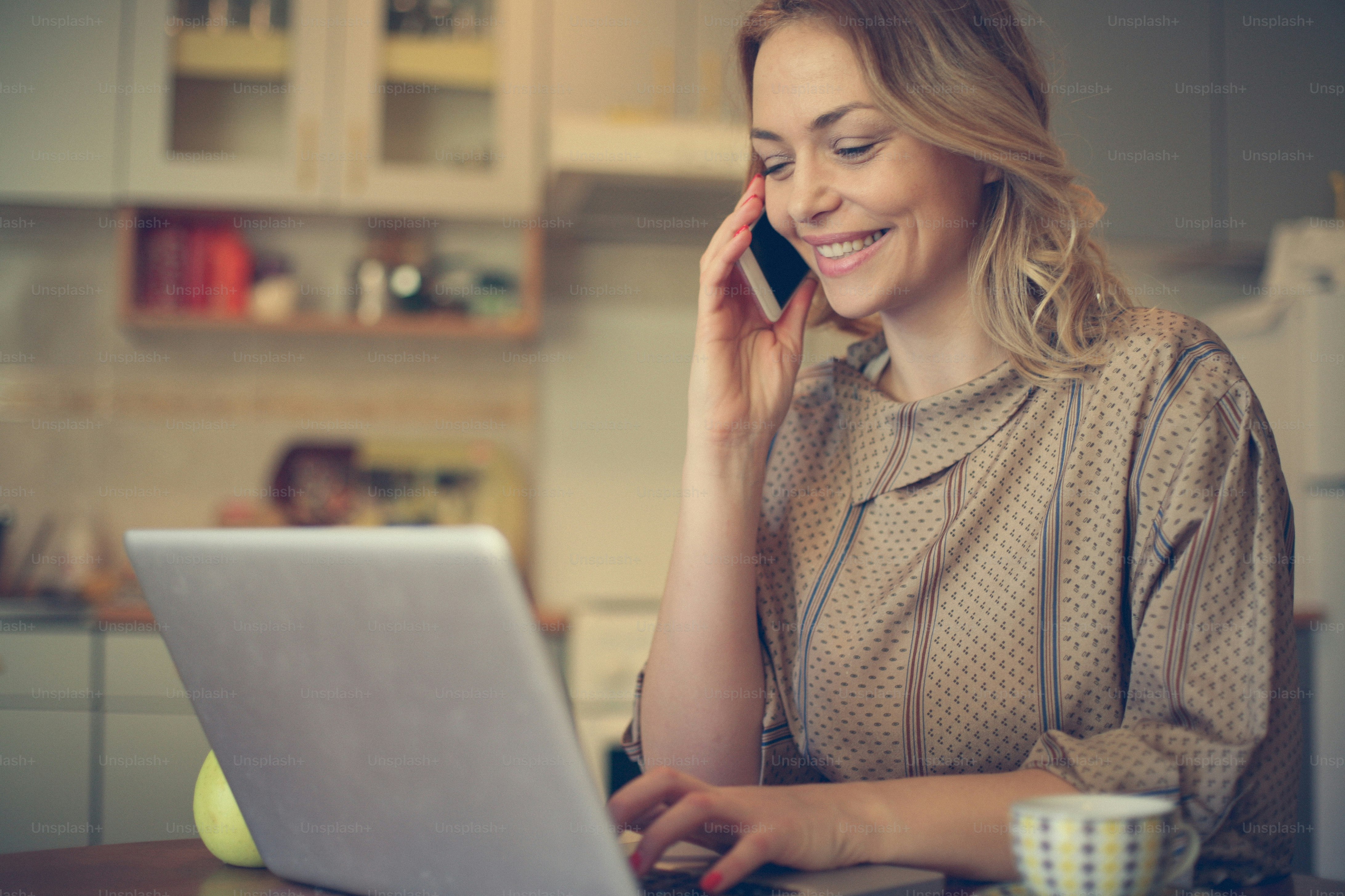 Pretty woman using smart phone and typing on laptop at home. photo ...