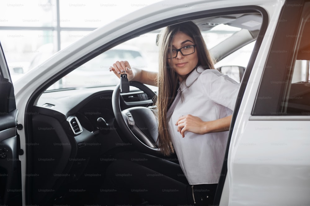 Giovane donna felice vicino all'auto con le chiavi in mano - concetto di acquisto di auto