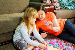 Mother and child daughter playing together, build from the constructor. cute mother play together indoor. Young mom with her child play together