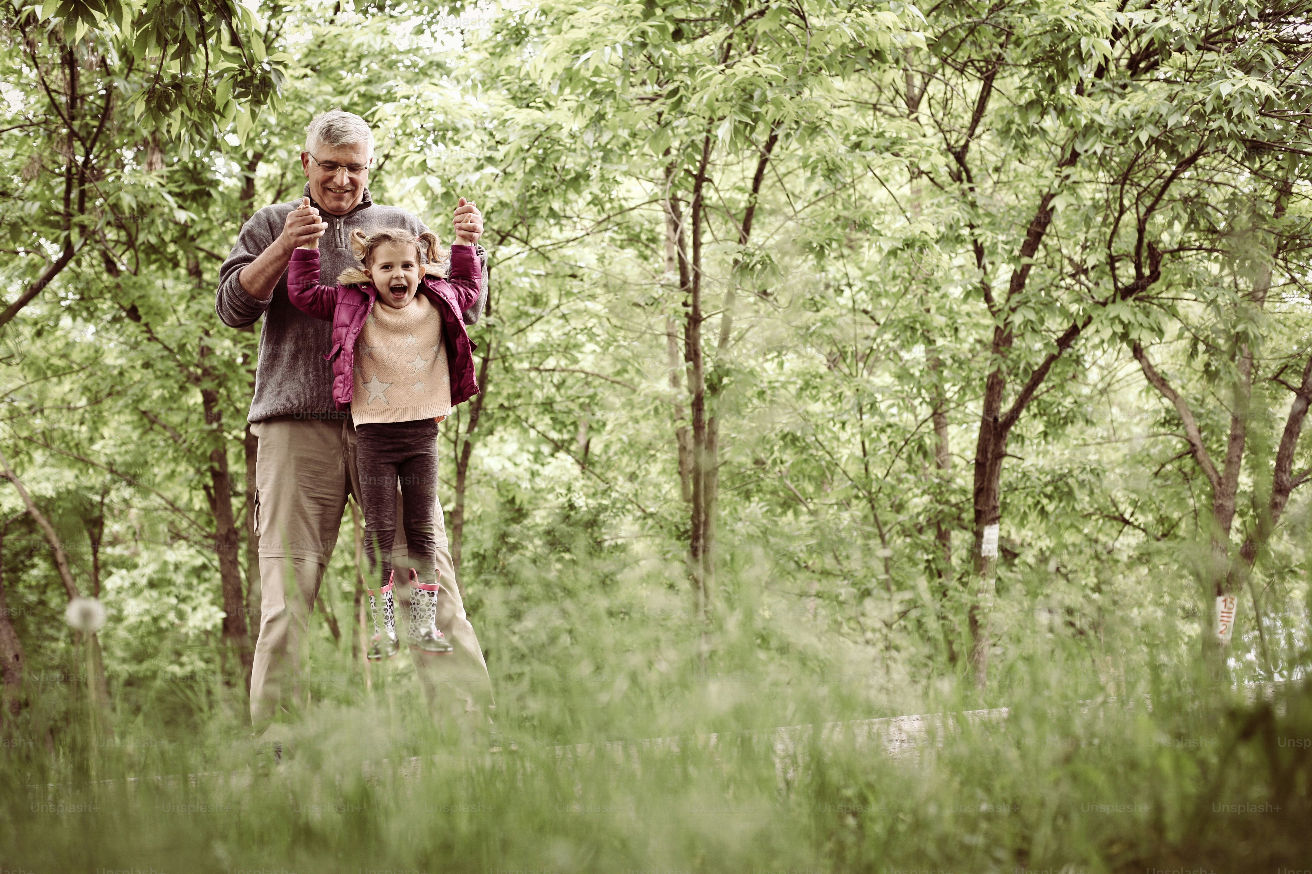 Happy kid playing with grandfather in the park. Space for copy.