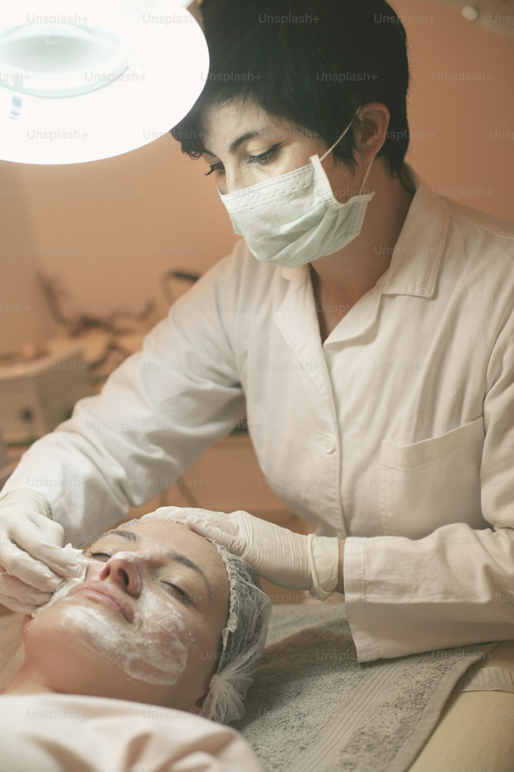 Young woman in a spa center. Lying on a massage table with a mask on her face. Ambient light and pilot lamps used.
