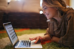 Beautiful blonde woman using her laptop in the comfort of her living room.