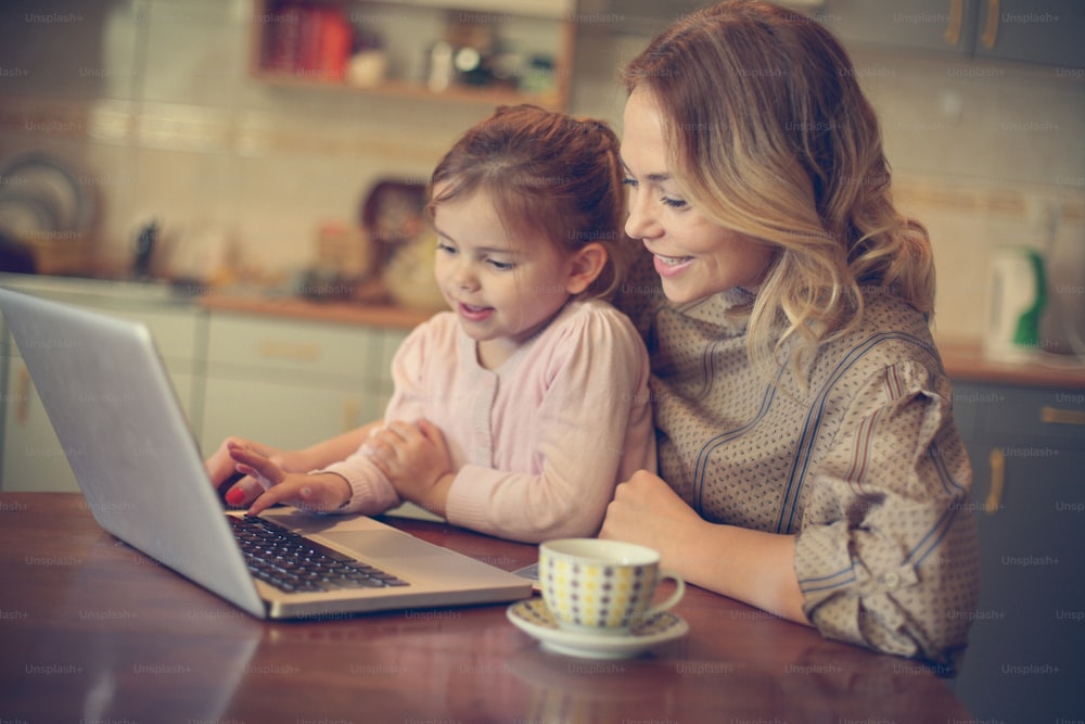 Mother with daughter using laptop in the kitchen.