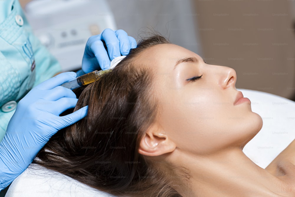 Needle mesotherapy. Cosmetic been injected in woman's head. Thrust to strengthen the hair and their growth